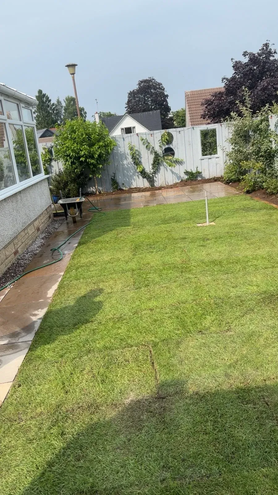 Fresh turf lawn laid alongside a new Indian sandstone patio in a Stirling rear garden